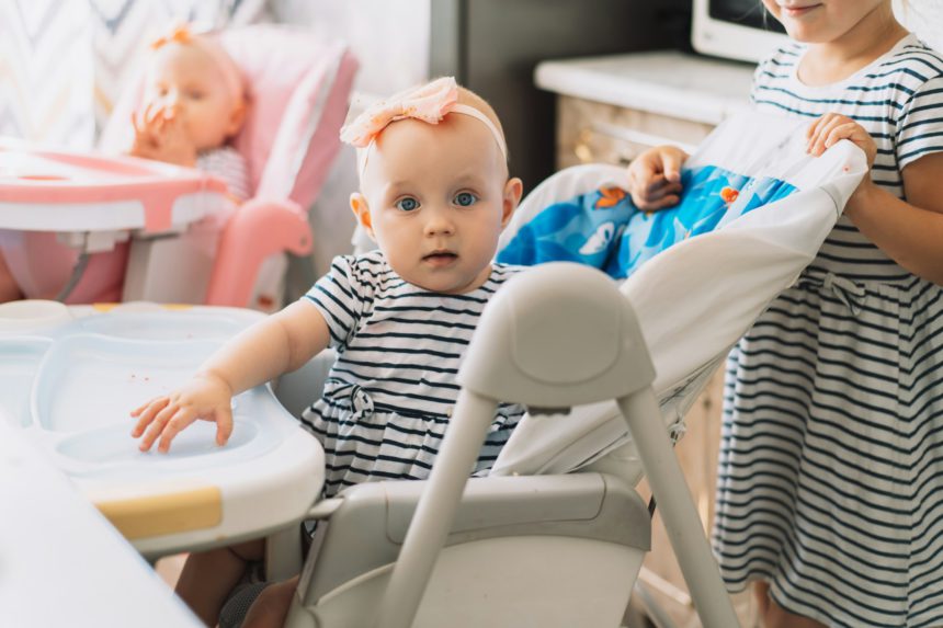 Twins sitting on chairs and older sister