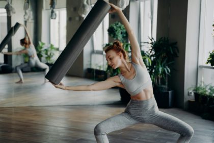 Young woman exercising with pilates foam roller in half sitting position